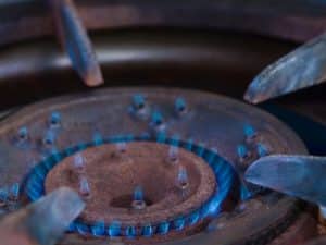 Close-up of a gas stove burner with low flame, highlighting a common issue of gas stove not heating.