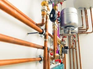 A plumber inspecting a blocked gas line, causing a potential safety hazard.