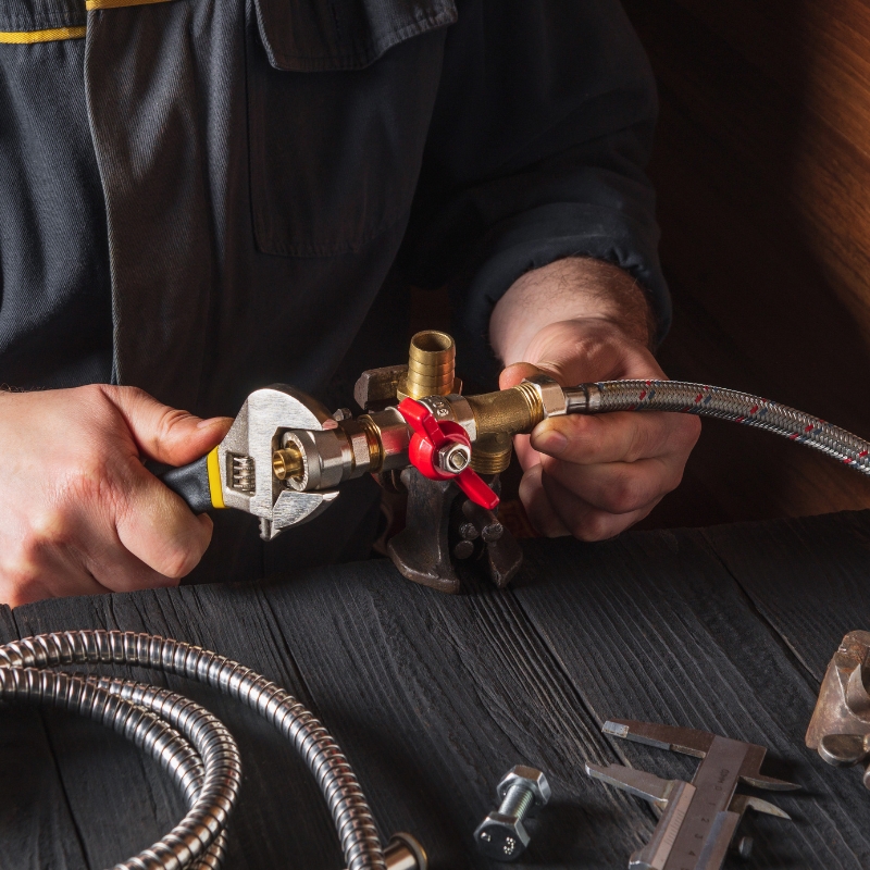 Technician working on gas fitting connections with tools on a table, showcasing professional gas fitting Sydney services.