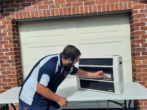 Technician inspecting a gas heater outdoors, highlighting potential gas heater problems and maintenance needs.