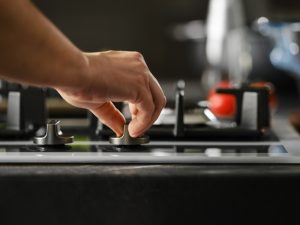 Potential gas stove issues: Close-up of a hand adjusting a gas stove knob.