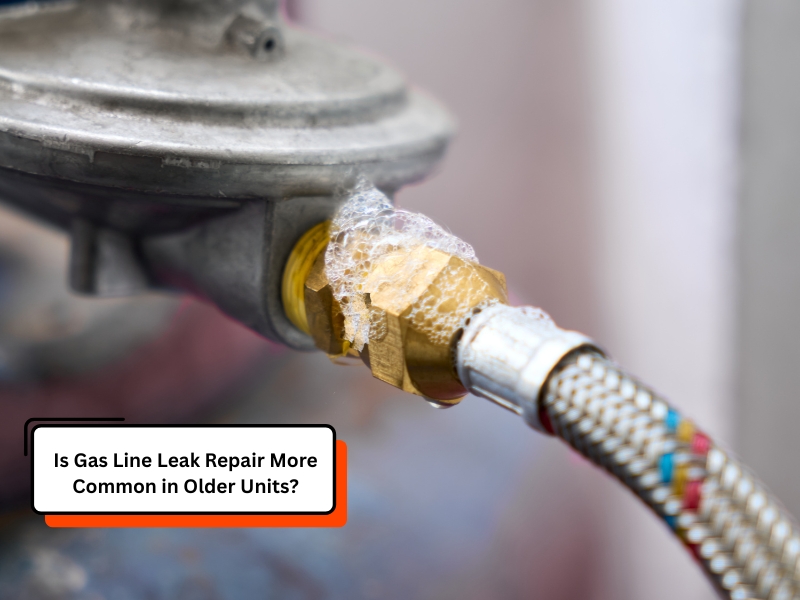 Close-up of a gas line leak with visible soap bubbles forming around a brass connector, indicating a leak at the joint of an older gas appliance.