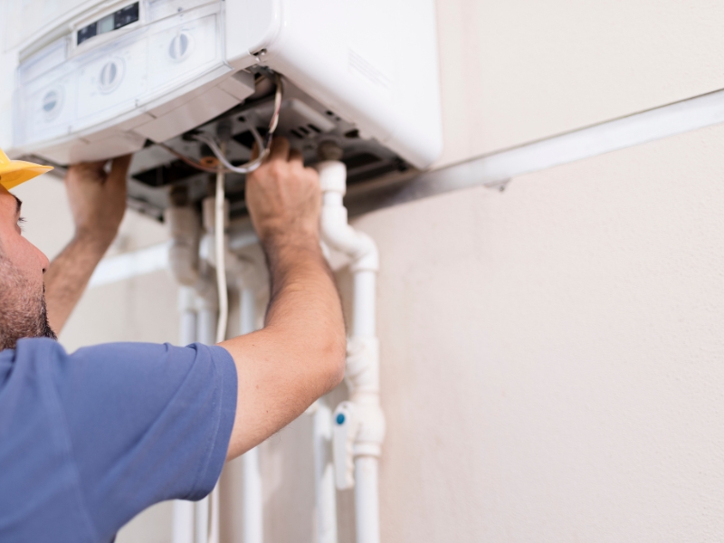 Technician installing a boiler connected to a natural gas line tap.