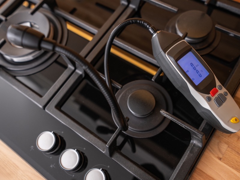 Digital device used for gas pipeline leak detection placed on a modern gas stove.